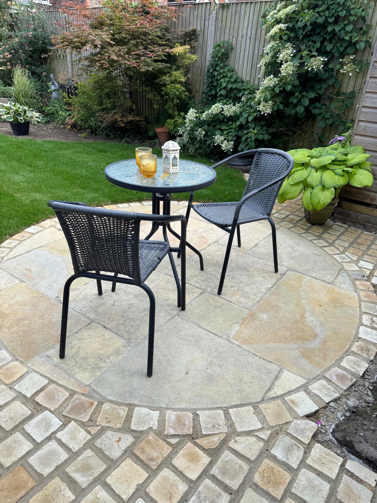 Circular natural stone patio with cobble sett border in a mature garden