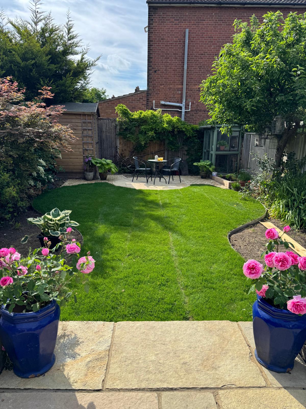 Complete garden scheme with sandstone patio, fresh lawn, roses in planters and dining area